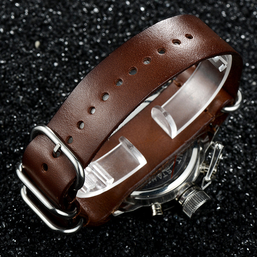 luxury men military wrist watch with a silver case and brown leather strap on a textured black background